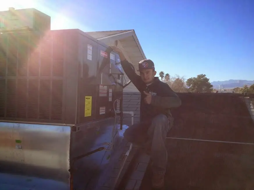 HVAC technician performing Air Duct Cleaning on a rooftop unit in Clinton